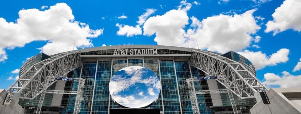 Wide exterior view of AT&T Stadium beneath the sky mirror