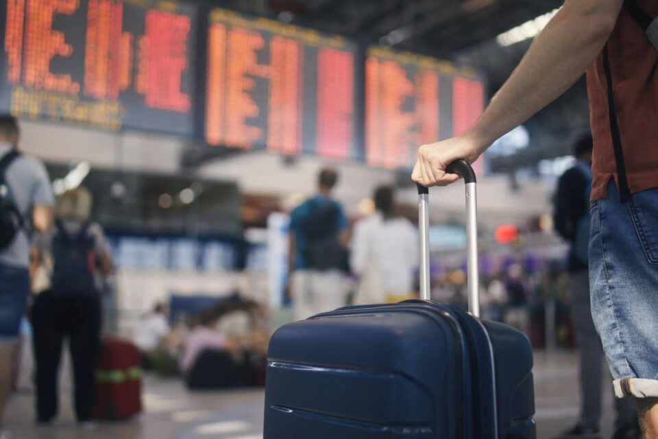 Traveller waiting beside an airport departures board