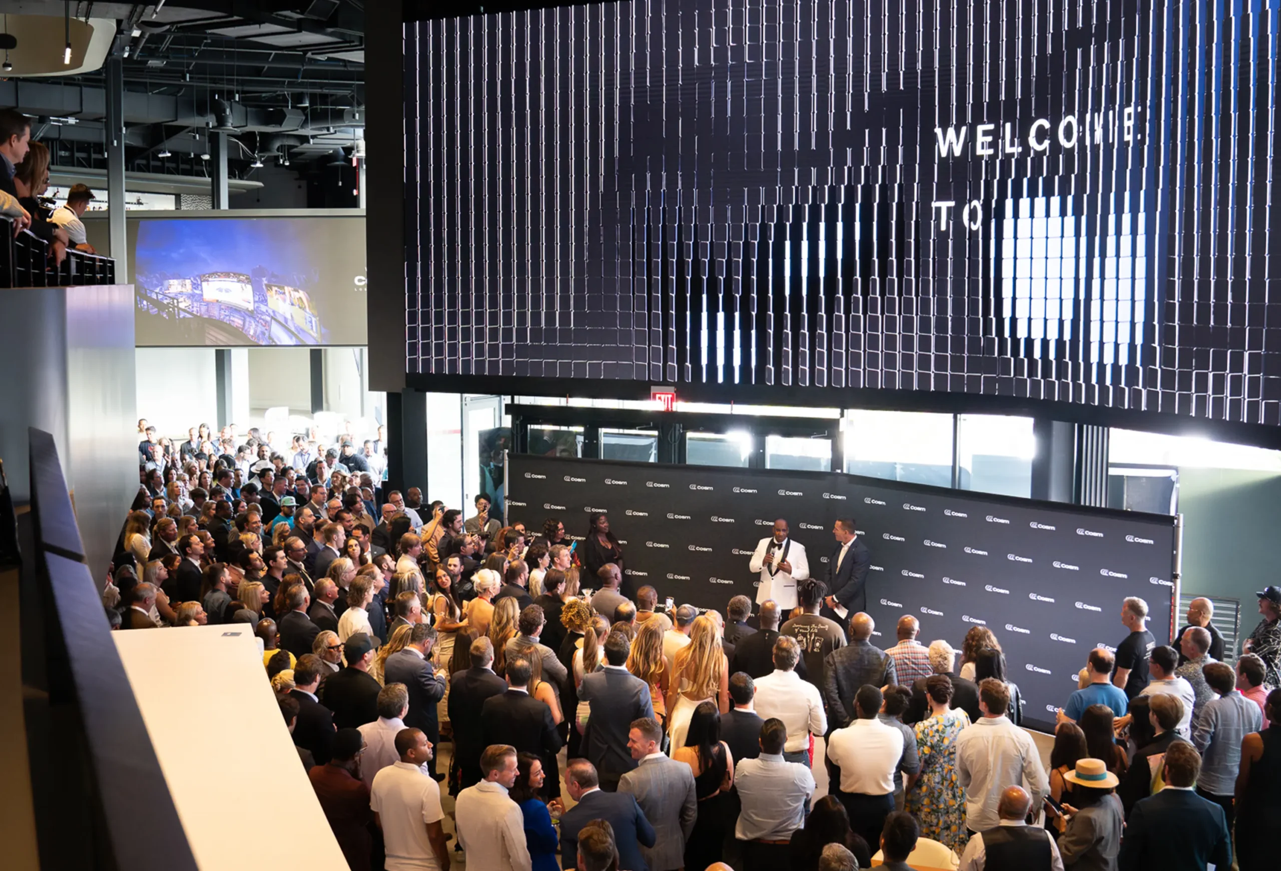 Guests watching an event beneath a large screen at Cosm