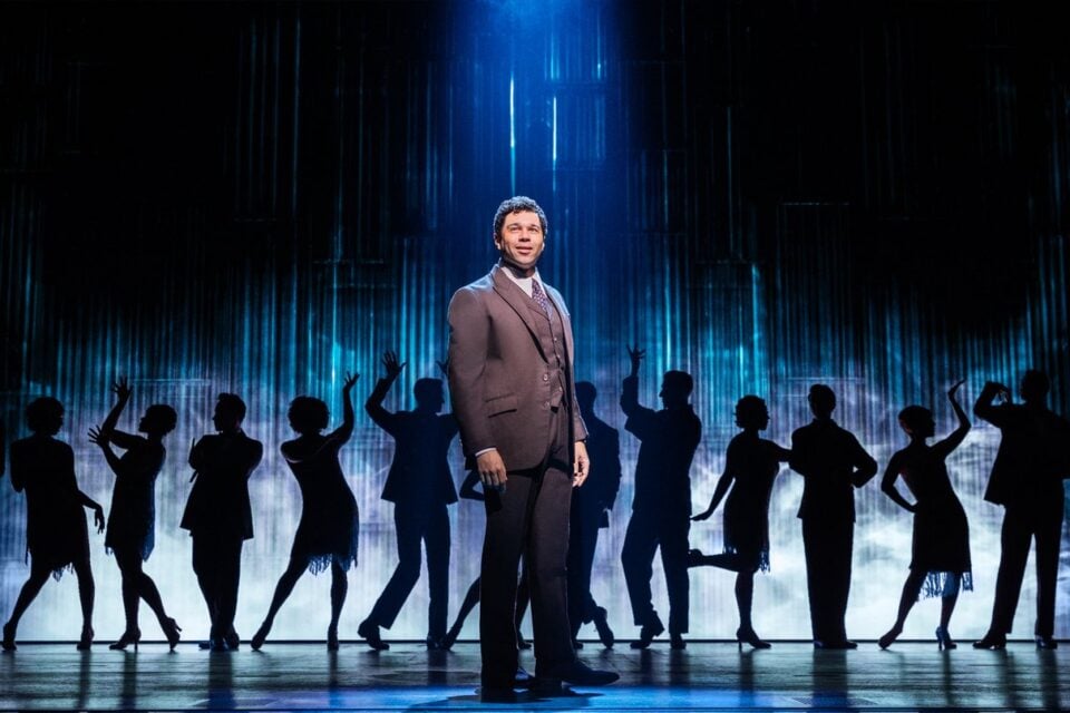 A man before silhouetted party dancers in The Great Gatsby Broadway