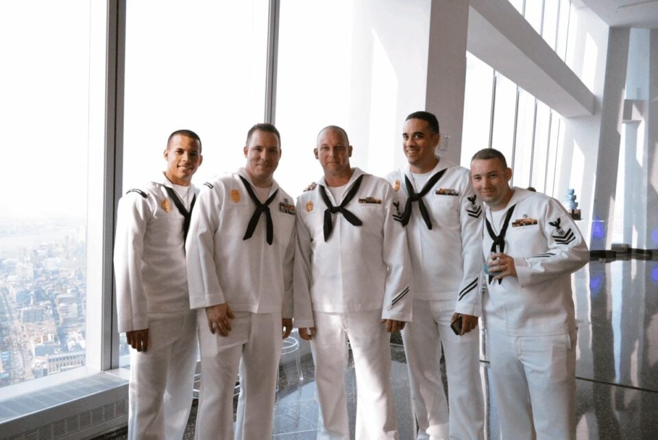 Visitors in naval uniforms standing beside the windows at One World Observatory
