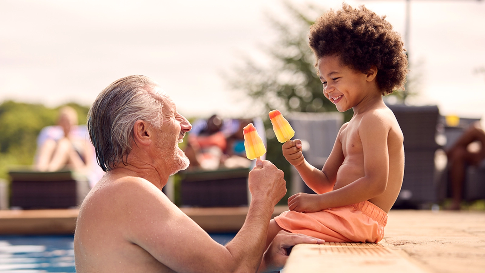 Grandfather and child beside a pool on holiday