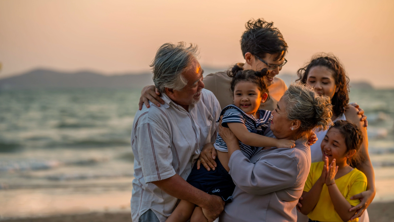 Multi-generation family enjoying a beach holiday at sunset