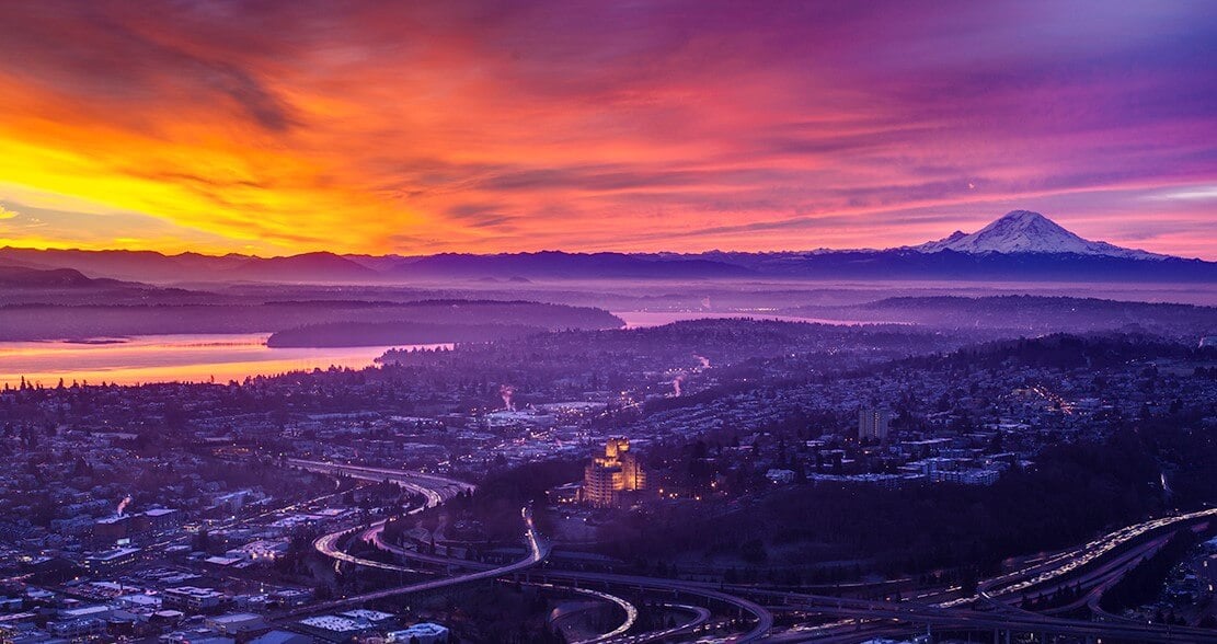 Mount Rainier glowing at sunrise beyond Seattle