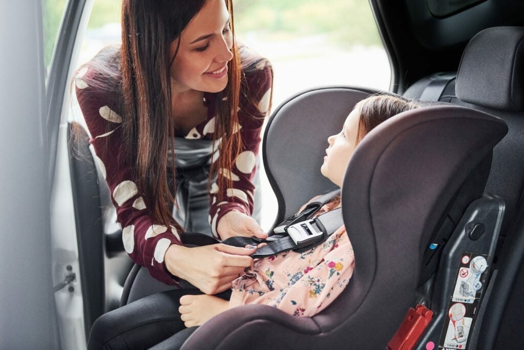 Äiti kiinnittää lapsen turvaistuimeen autossa
