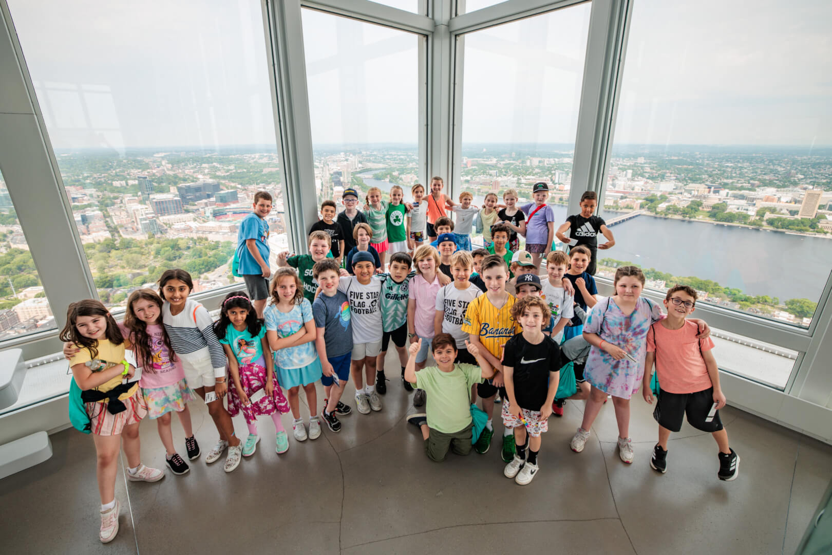 Children posing inside the View Boston observatory with the skyline behind them