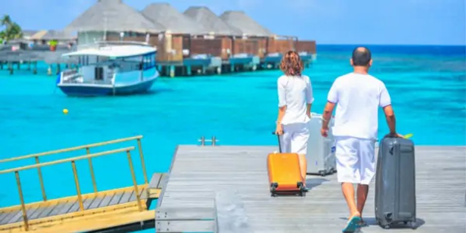 Two travellers walking with luggage beside a dock