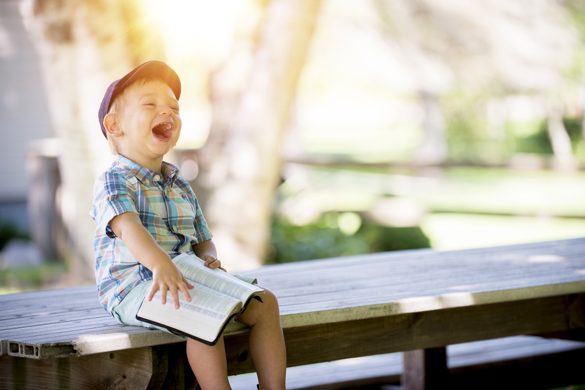 Child laughing while reading a book