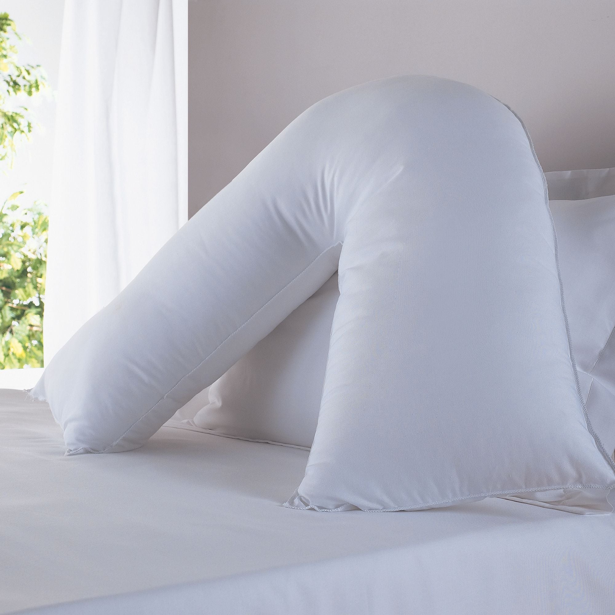 V shaped pillow arranged on a bed