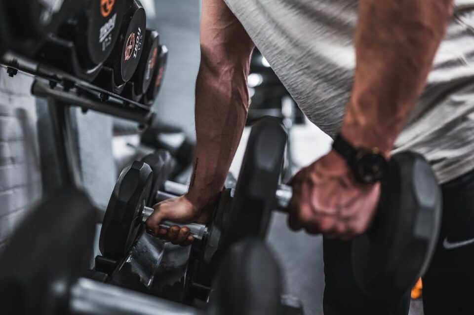 Person beim Krafttraining mit Hanteln im Fitnessstudio