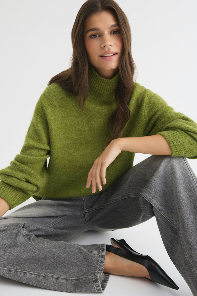 Model wearing Gina Tricot green knitted turtleneck sweater with wide-leg jeans