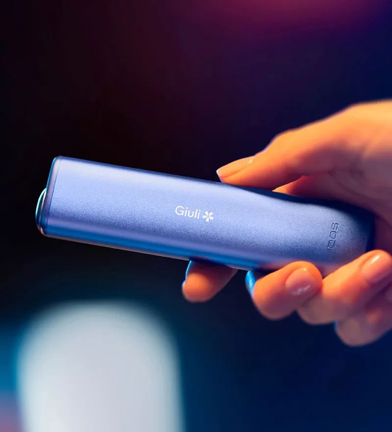 Dispositivo iqos con incisione mostrato in una scena lifestyle