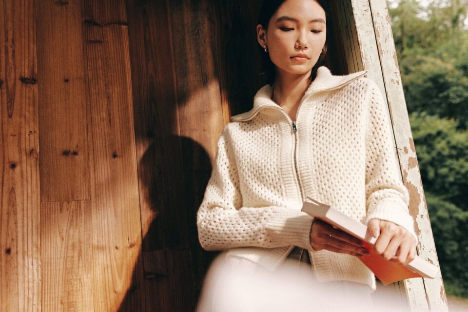 Donna con cardigan color crema in una scena lifestyle all'aperto