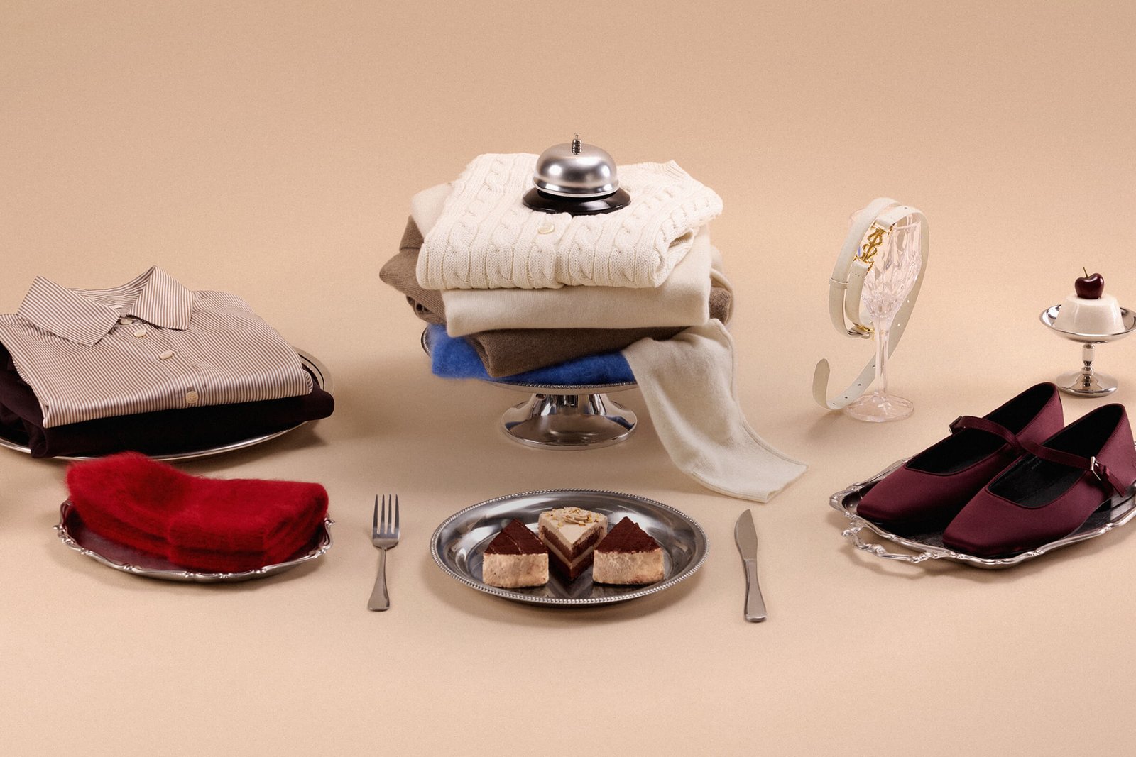 Composizione di capi in maglia, camicia, accessori e dessert su un tavolo