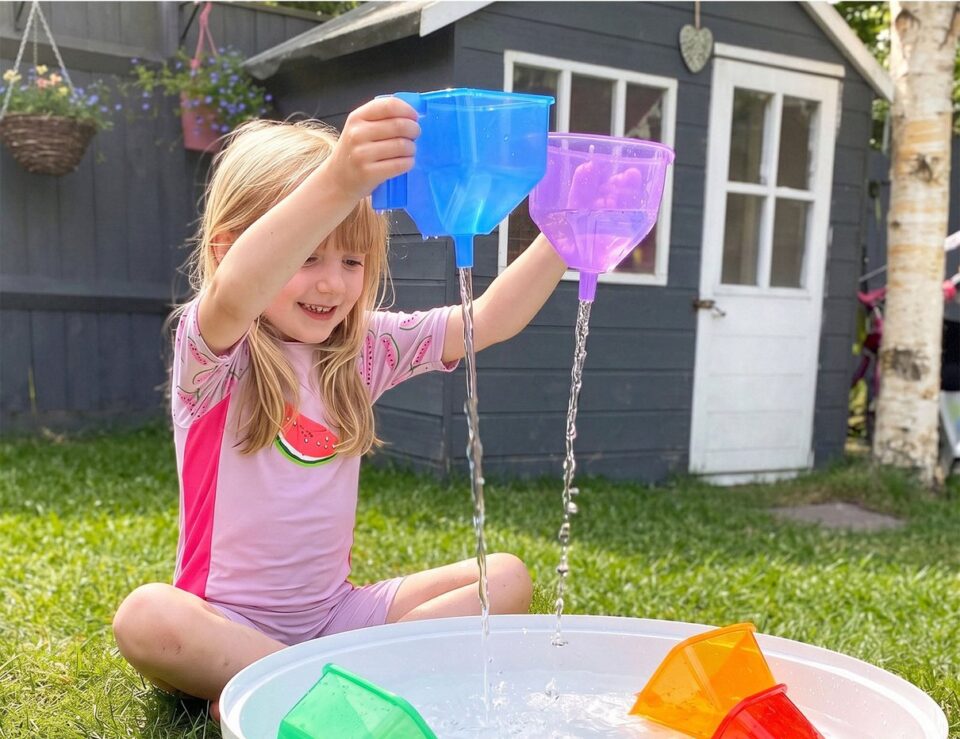Deep Tuff Tray with translucent funnels arranged for outdoor sensory play