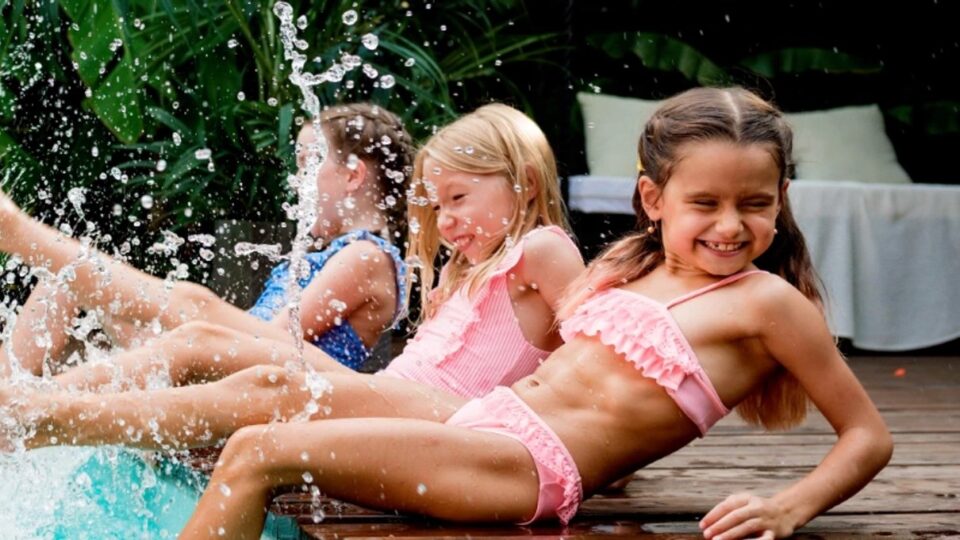 Children splashing in a swimming pool on a family holiday