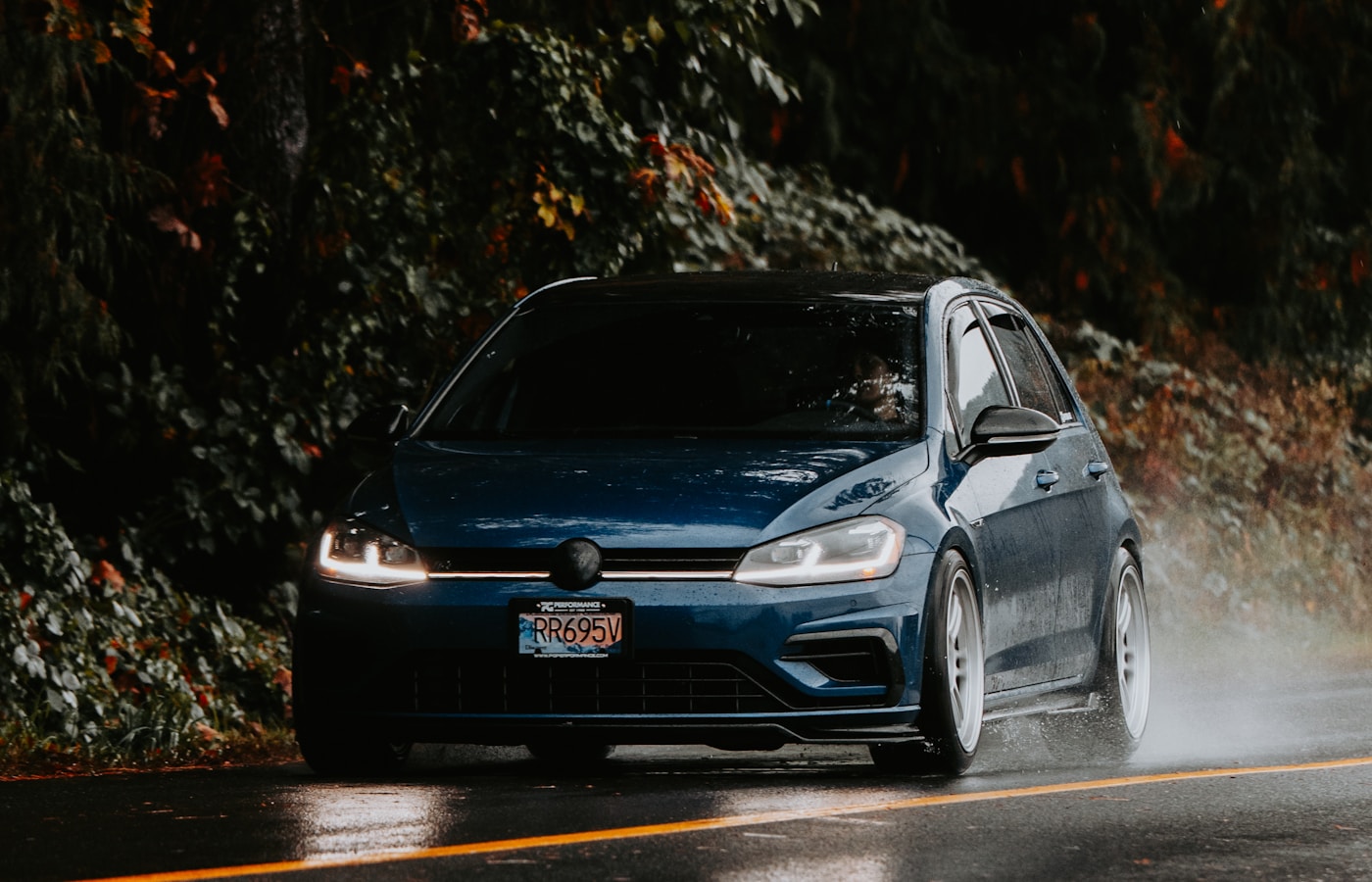 Blaues Auto fährt durch eine regennasse Herbststraße