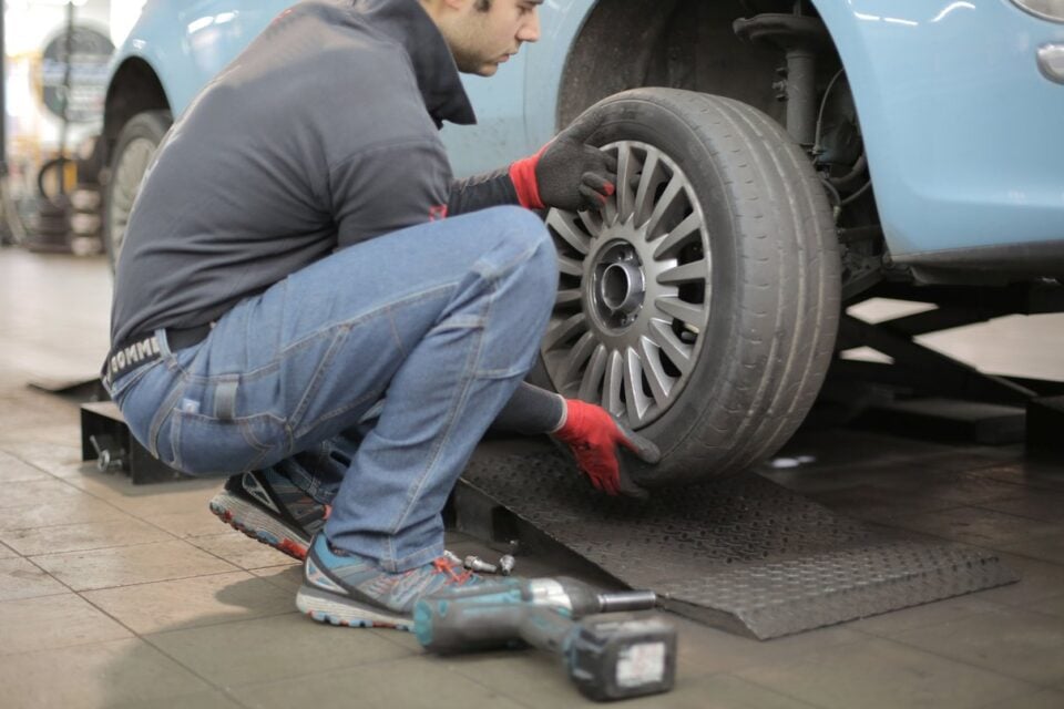 Mechaniker nimmt in einer Werkstatt ein Autorad ab