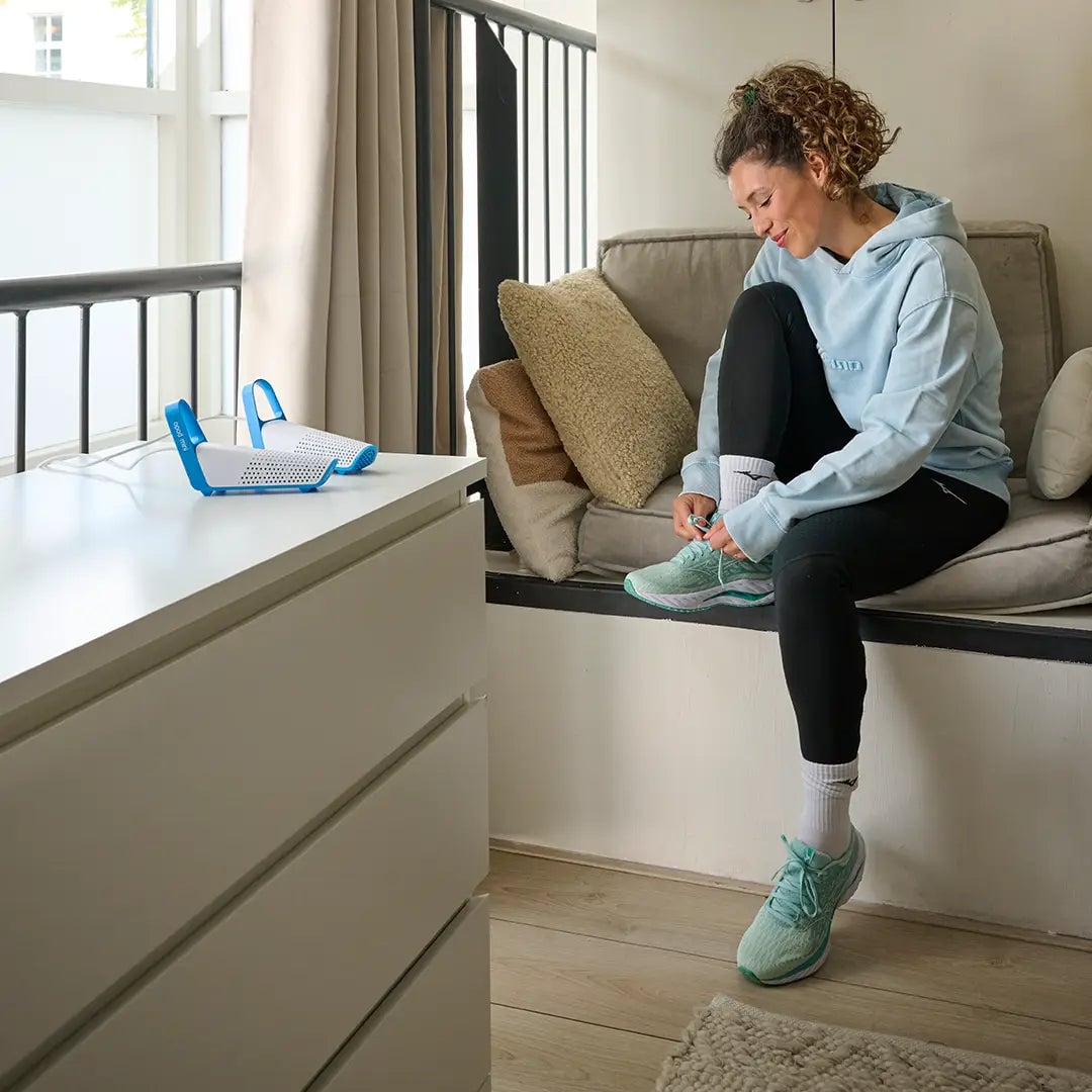 Vrouw die sportschoenen aantrekt naast een compacte Shoefresh Mini