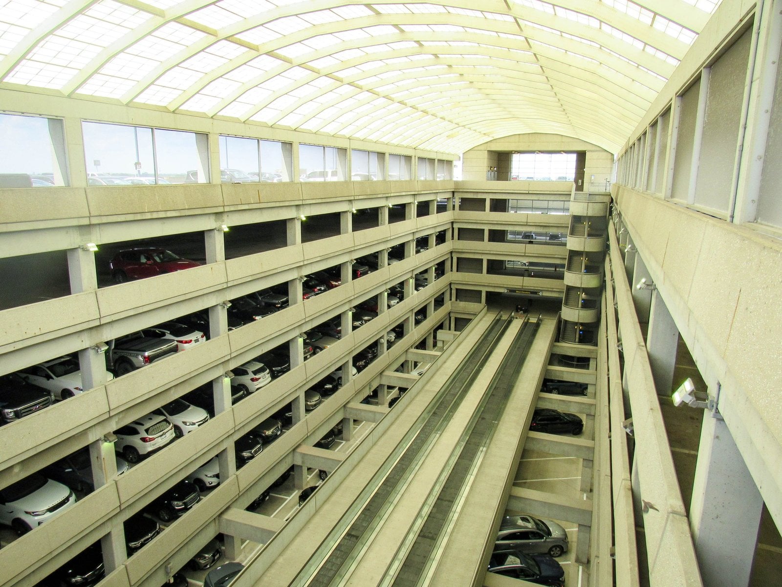 Interior view of an airport parking garage with cars and concrete ramps