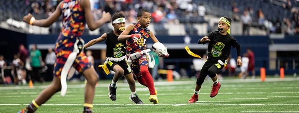 Children playing flag football on the AT&T Stadium field