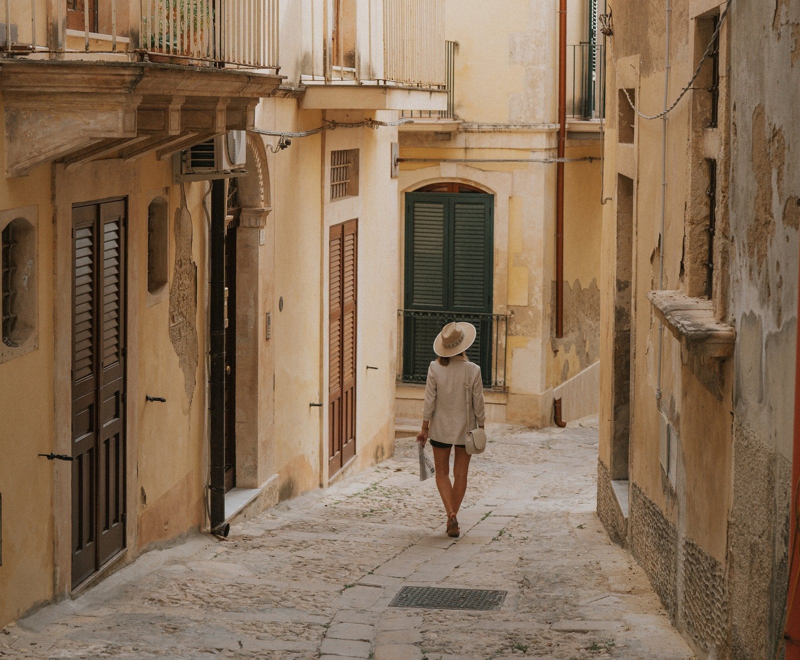 A visitor walking along a stone street in Cefalù, Sicily