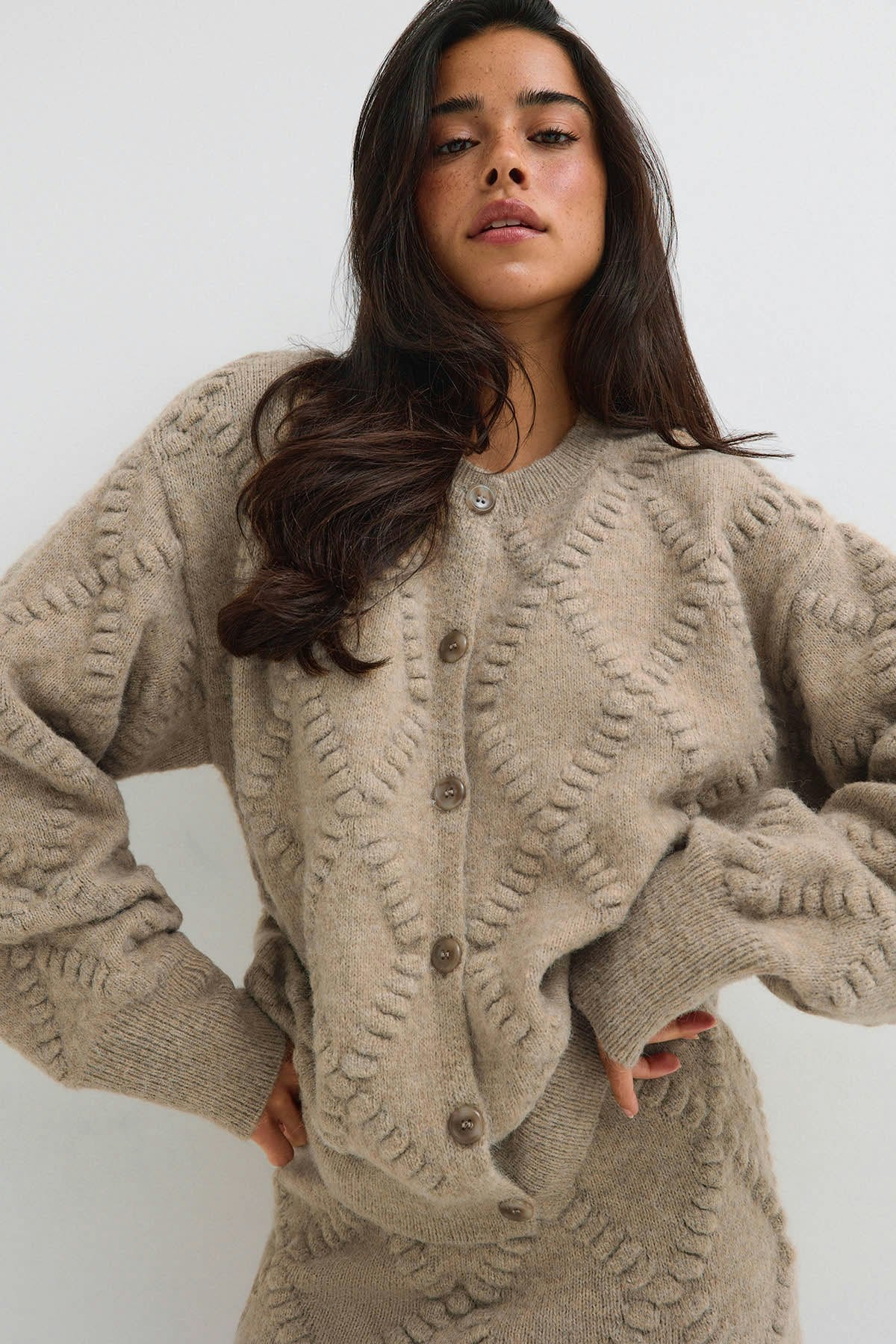 Beige cable-knit cardigan styled with a matching skirt