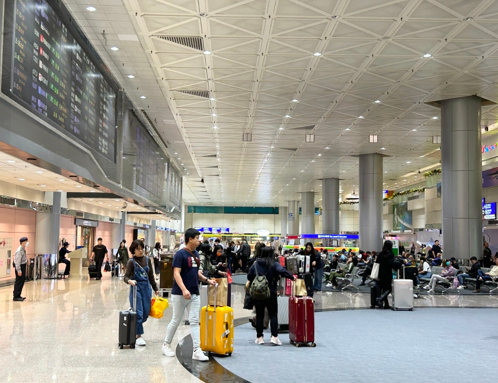 Passengers with luggage inside a busy airport terminal