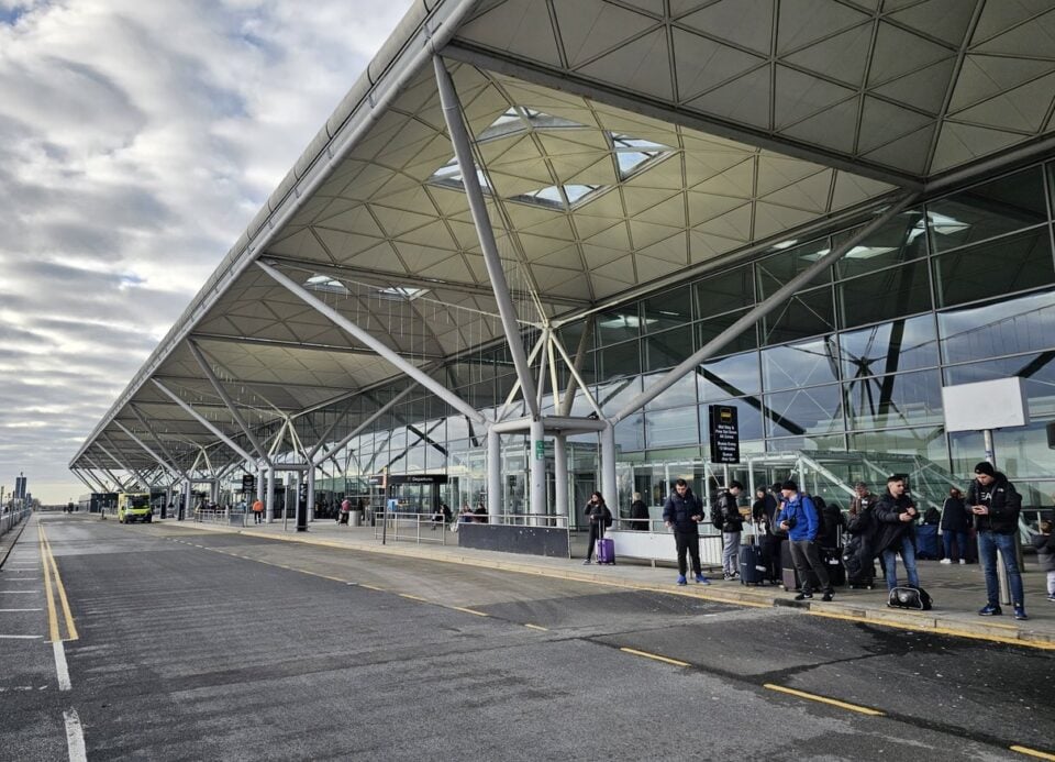 Covered airport terminal forecourt with travellers and vehicles