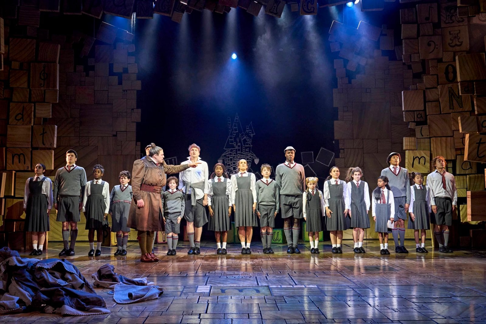 An earlier company image shows the production’s stage world.