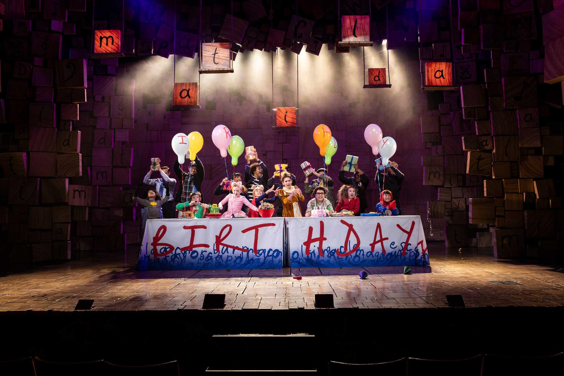 Cast performing in a Matilda production scene