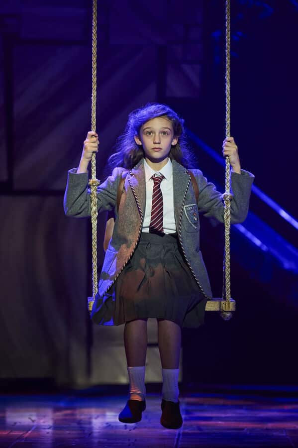 A young performer plays Matilda on a swing in a UK tour scene
