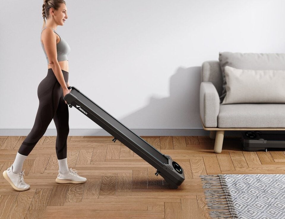 A person carrying the Merach T26B1 compact treadmill