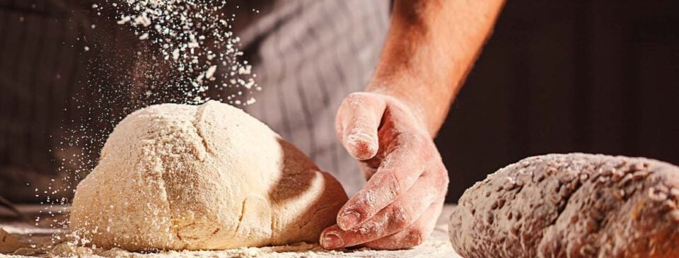 Hands shaping dough on a flour-dusted work surface