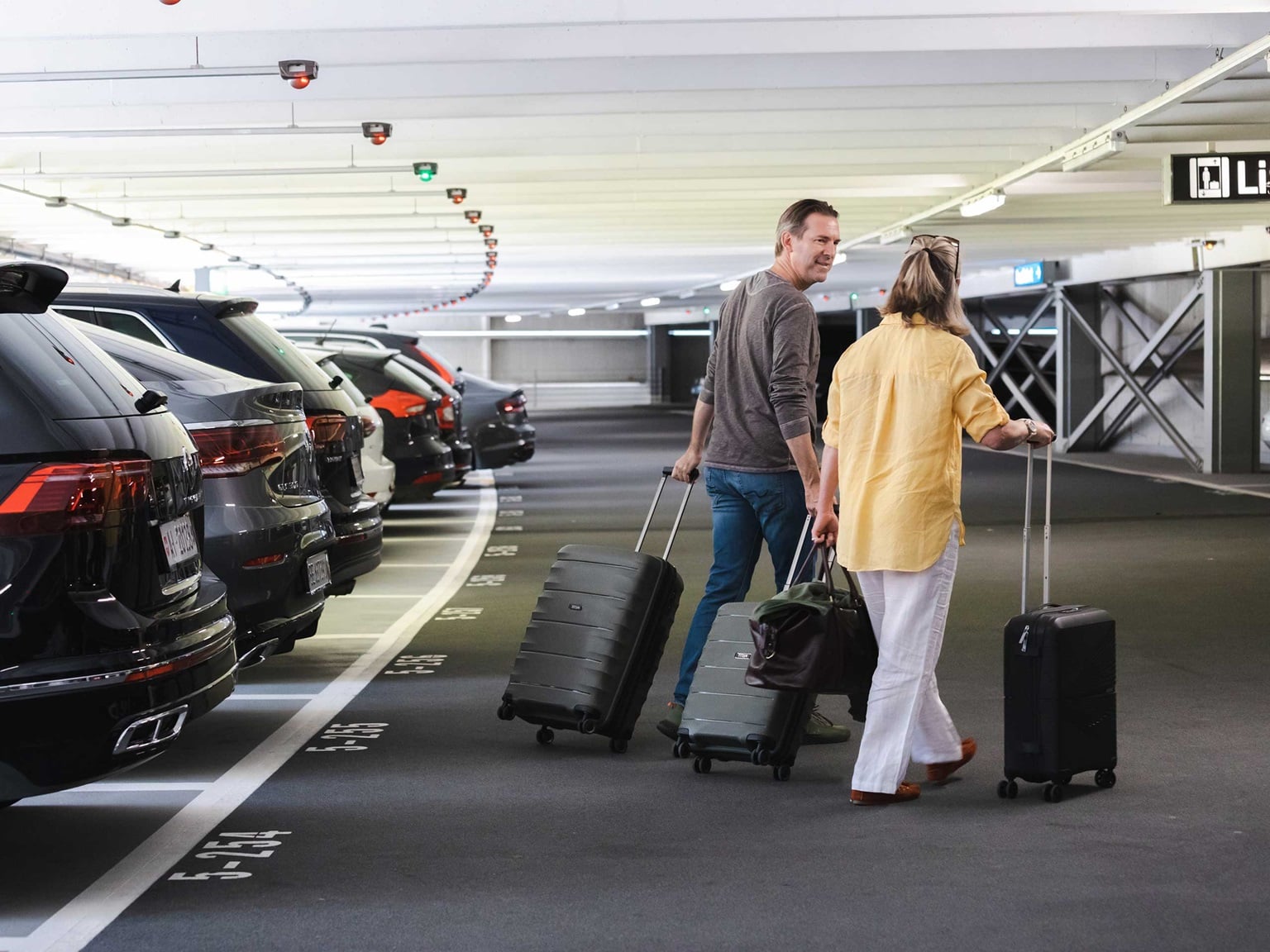 Travellers in an indoor airport parking area