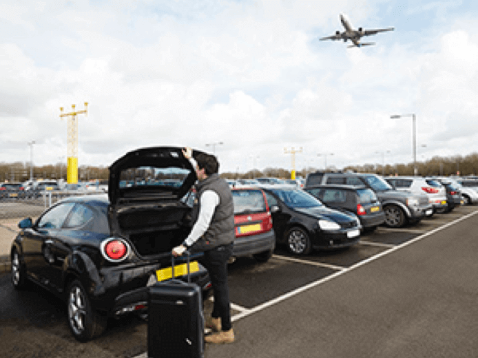 Traveller loading luggage into a car in an airport car park