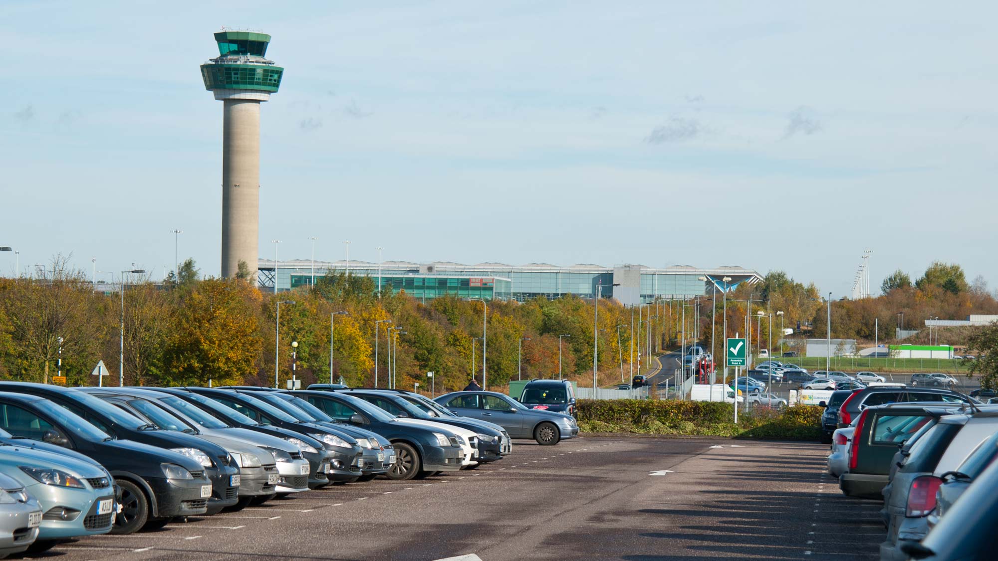 Cars parked near an airport terminal and control tower