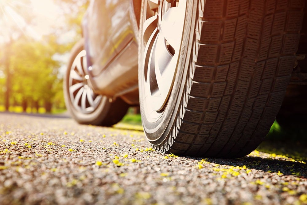 Autoreifen auf einer sonnigen Straße mit grüner Umgebung