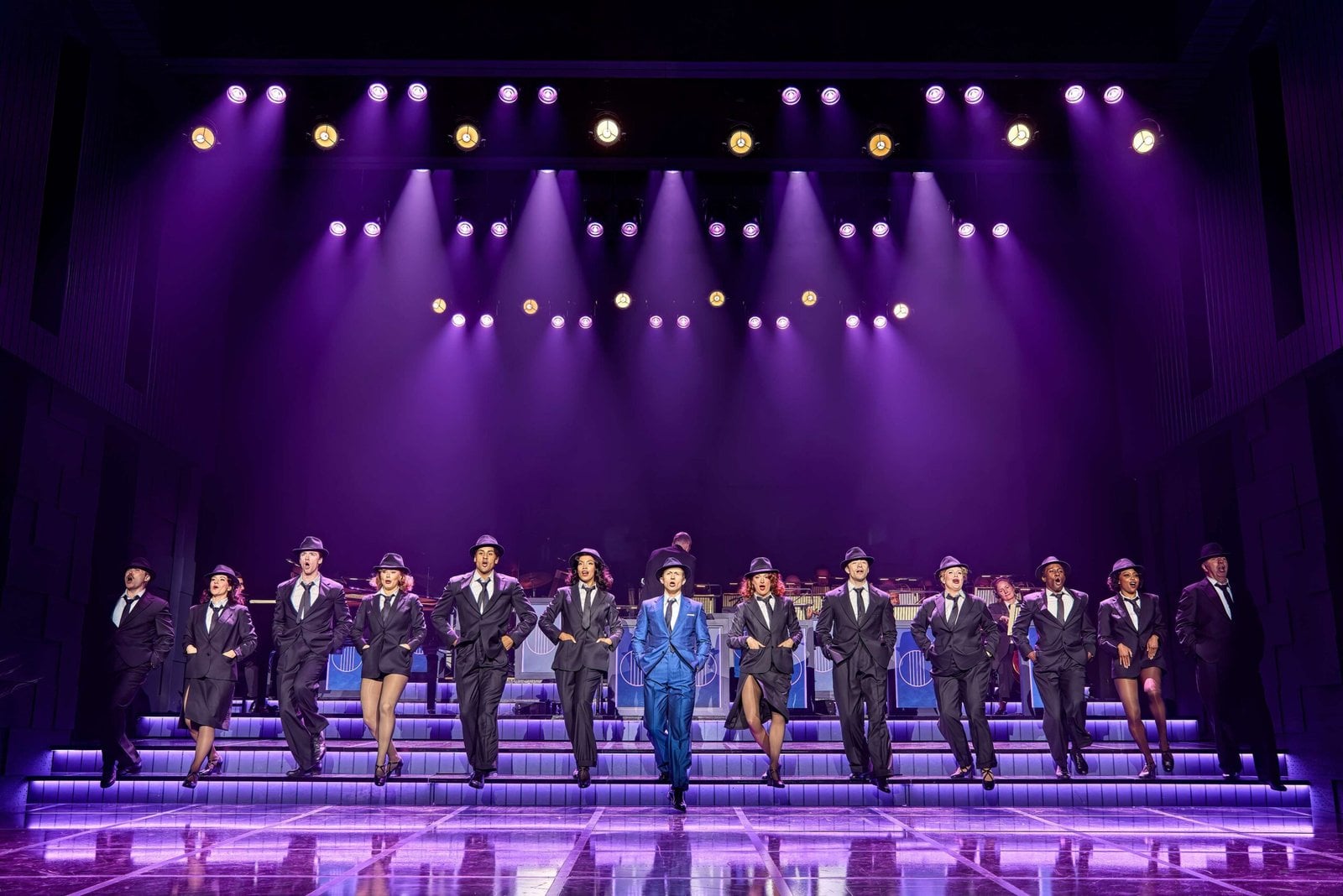 The Sinatra the Musical ensemble performs beneath purple lights