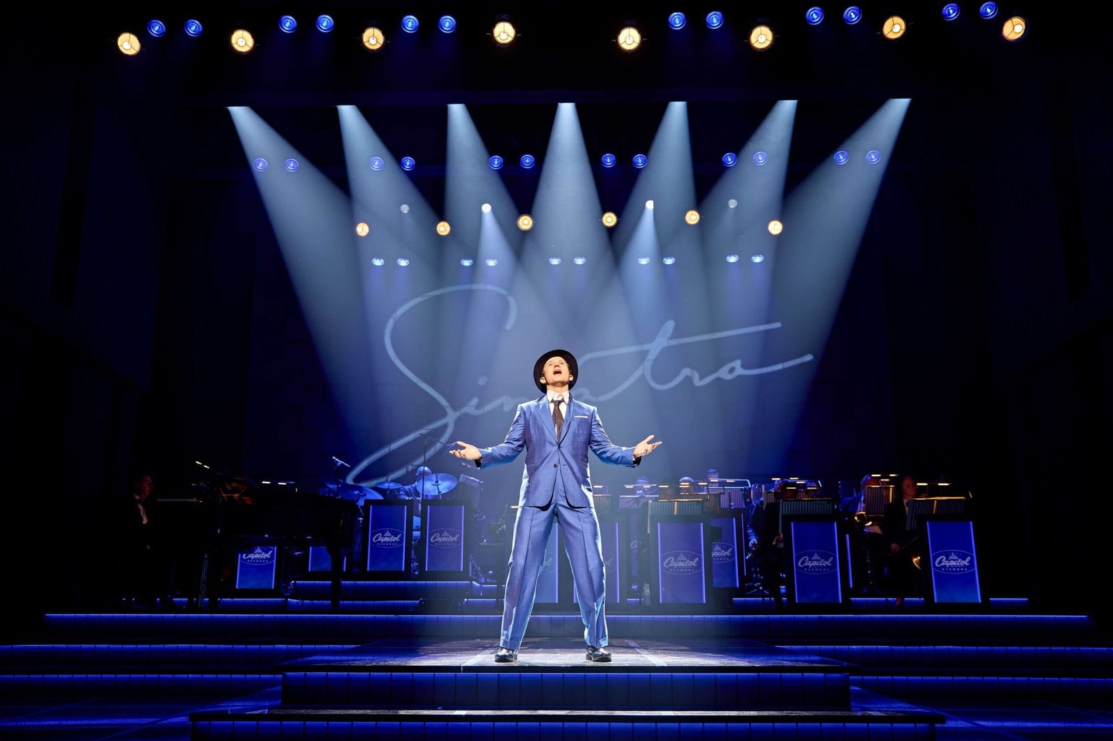A solo singer performs beneath spotlights on the stage
